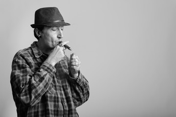 Studio shot of mature gangster man lighting while smoking cigar