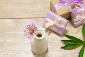 Fototapeta na wymiar Gift boxes for Mother's Day. Flowers in a vase. Wooden table. The atmosphere of warmth and comfort