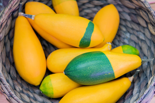 Top view of small decorative pumpkins (Kleine Birne Bicolor) in whicker basket.