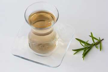 Rosemary tea in Armudu glass with branch of rosemary on white table as background