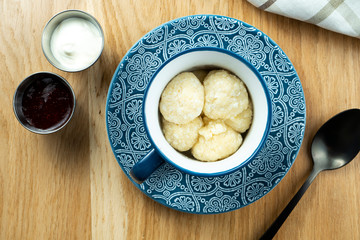 lazy dumplings with cottage cheese in a blue bowl with sour cream and strawberry jam. Top view. Food flat lay. Ukrainian cuisine. Dessert