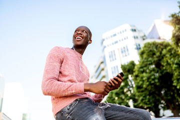 Side of young black man listening to music with headphones and mobile phone