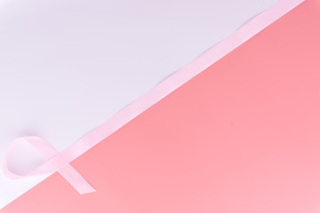 Pink ribbon breast cancer on pink and white background with copy space for text. Flat lay, top view.
