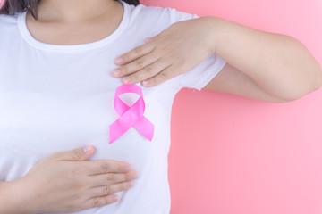 Obraz na płótnie Canvas Healthcare, medicine and breast cancer awareness concept. Closeup on woman chest with pink breast cancer awareness ribbon.