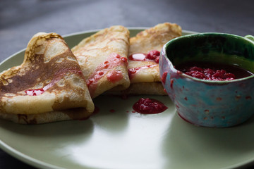 Blini triangles or crepes on plate with raspberry jam