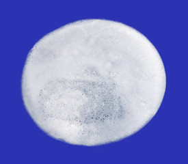 Clean and clear soap foam isolated on blue background. Circle of white soap foam
