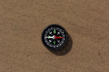 Fototapeta na wymiar Compass pointing East laying on sand beach