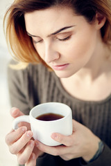 portrait of young attractive smiling woman with a cup of morning coffee or tea.