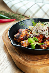 Grilled chicken wings in honey and beer sauce served in a decorative pan with herbs. Close up, selective focus. Wooden background. Food photo