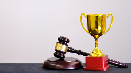 Judge's gavel and trophy on white background. Symbol for jurisdiction. Law concept a wooden judges gavel on table in a courtroom or law enforcement office
