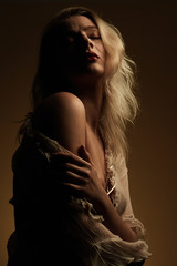 Art fashion portrait of sexy sensual young blonde woman with red lips and topless. Conceptual artistic photo of posing beautiful model in dramatic subdued light