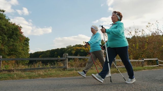 Elderly senior women practicing Nordic walking outdoors, healthy lifestyles in old age. Slow-motion 4k video