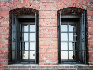 Two window on a red brick wall