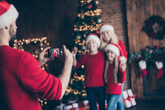 Blurry photo of dad taking photo of two children with mom near decorated newyear tree indoors family comfort x-mas spirits wear santa caps and red sweaters