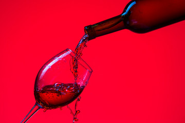 Bottle and Glass or Wine Isolated Over Red Background. Horizontal Image