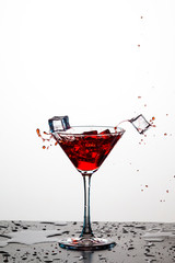 Action Splash Photography. Red Wine Glass With Splashes Against White Background. Vertical Image