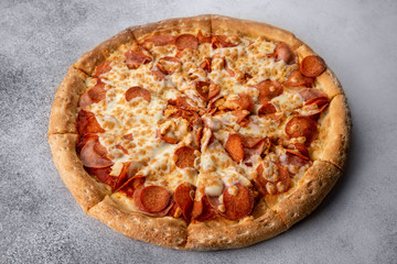 Delicious hot homemade Pepperoni pizza on the wooden table. Pepperoni Pizza - Fresh homemade pizza with pepperoni, cheese and tomato sauce on rustic black stone background with copy space.