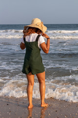 A young African lady in a sun hat playing by the beach