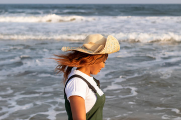 A young African lady in a sun hat playing by the beach