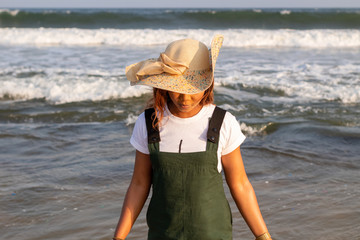 A young African lady in a sun hat playing by the beach