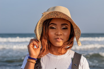 Portrait of a young African lady wearing a sun hat at the beach