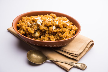 Wheat Laapsi/Lapsi/Shira/Halwa is an Indian sweet dish made of broken wheat or Daliya pieces and ghee along with nuts, raisins and dried fruits. It's a healthy food. served in a bowl, selective focus