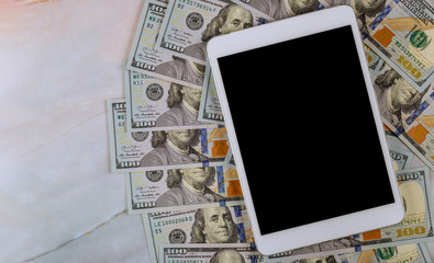 Fototapeta na wymiar American banknotes hundred dollar bills on digital devices tablet with e-commerce concept