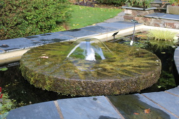 Round wheel water feature in garden pond