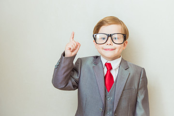 Smiling child boy pointing his index finger at something on white background. Success, creative and innovation business concept