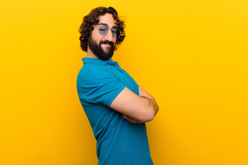 young crazy man smiling to camera with crossed arms and a happy, confident, satisfied expression,...