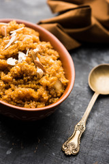 Wheat Laapsi/Lapsi/Shira/Halwa is an Indian sweet dish made of broken wheat or Daliya pieces and ghee along with nuts, raisins and dried fruits. It's a healthy food. served in a bowl, selective focus