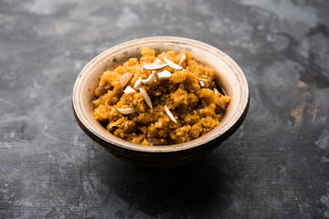 Wheat Laapsi/Lapsi/Shira/Halwa is an Indian sweet dish made of broken wheat or Daliya pieces and ghee along with nuts, raisins and dried fruits. It's a healthy food. served in a bowl, selective focus