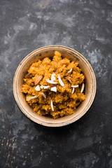Wheat Laapsi/Lapsi/Shira/Halwa is an Indian sweet dish made of broken wheat or Daliya pieces and ghee along with nuts, raisins and dried fruits. It's a healthy food. served in a bowl, selective focus