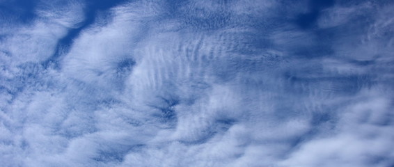 Faszinierende vom Winde verwehte weiße Wolken am blauen Himmel