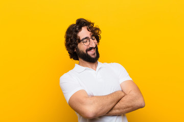 young crazy man laughing happily with arms crossed, with a relaxed, positive and satisfied pose...
