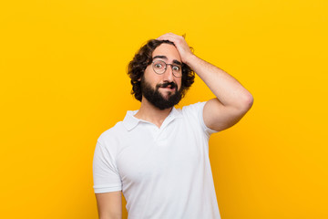 young crazy man panicking over a forgotten deadline, feeling stressed, having to cover up a mess or mistake against yellow wall