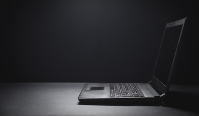 Black laptop on the black office desk. Technology concept