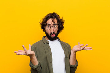 young crazy man shrugging with a dumb, crazy, confused, puzzled expression, feeling annoyed and...