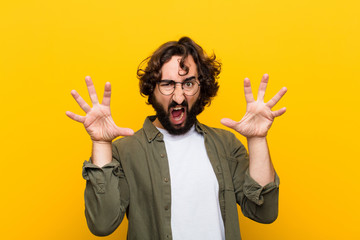 young crazy man screaming in panic or anger, shocked, terrified or furious, with hands next to head...