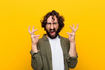 young crazy man screaming with hands up in the air, feeling furious, frustrated, stressed and upset...
