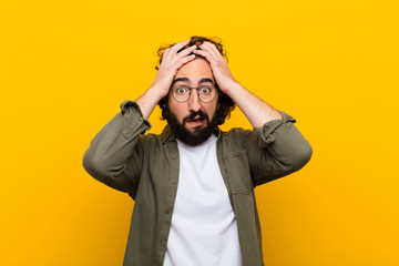 young crazy man feeling horrified and shocked, raising hands to head and panicking at a mistake...