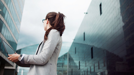 Young ambitious woman with a laptop in her hands on the background of the business center.