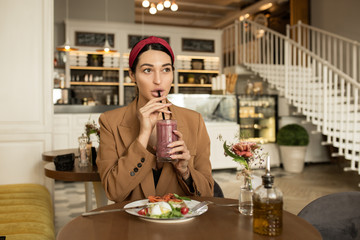 fashion woman at the bar at the table having lunch. Eating Food and Drinking a Cocktail
