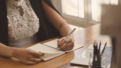 Cropped shot businesswoman writing on notebook paper.