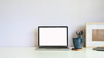 Copy space mockup laptop, coffee mug, pencil with photo frame on workspace desk.