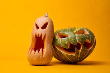 Image of two creepy halloween pumpkins on empty orange background.