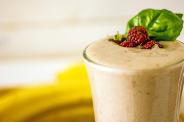 Appetizing milkshake raspberries. Delicious creamy cocktail with fresh berries and banana on blurred white background. Raspberry smoothie with banana and coconut milk. The concept of healthy diet