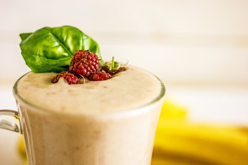 Appetizing milkshake with raspberries Delicious creamy cocktail with fresh berries and banana on blurred white background. Raspberry smoothie with banana and coconut milk. Close-up