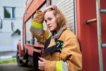 Image of firefighter woman next to fire engines on street.