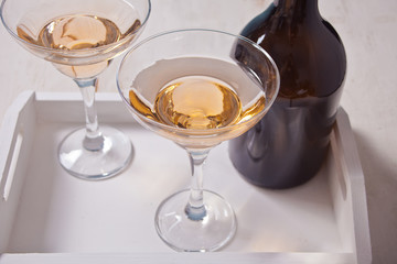White wine in a glasses, bottle on the white wooden tray. Dinner for two.